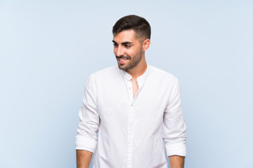 Handsome man with beard over isolated blue background smiling a lot