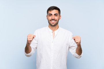 Naklejka premium Handsome man with beard over isolated blue background celebrating a victory in winner position