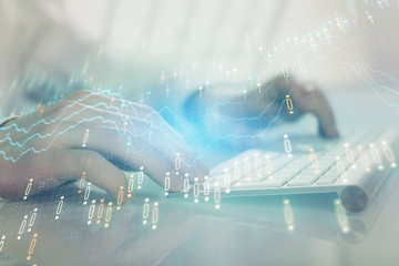Double exposure of graph with man typing on computer in office on background. Concept of hard work.
