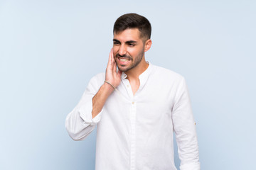 Handsome man with beard over isolated blue background with toothache