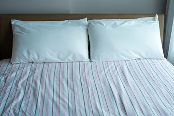 White pillows on a soft bed with pink sheets