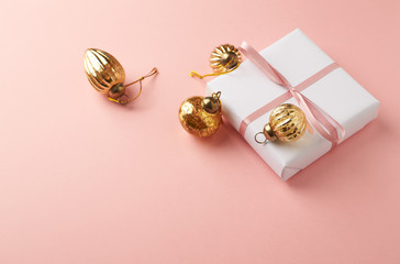 Christmas baubles and Christmas present. Pink paper background. Close up. Copy space. 
