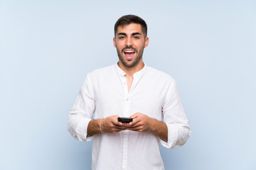 Handsome man with beard over isolated blue background surprised and sending a message