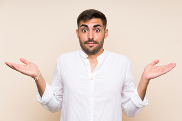 Handsome man with beard over isolated background having doubts with confuse face expression