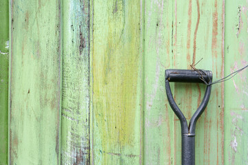 old shovel or hoe handle on vintage green wooden wall or table and floor for farmer and agriculture at countryside or labor day with space