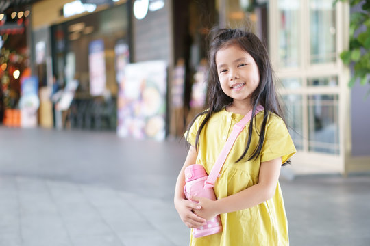 Asian Child Cute Or Kid Girl Smiling Happy And Sling Water Bottle Or Flask On Holiday For Waiting Study To Summer Special Classes And Thinking For New Idea At Kindergarten Or Street School And Travel