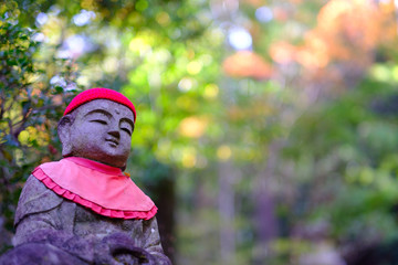 Japanese god statue with red apron in mitakidera temple garden, Hiroshima