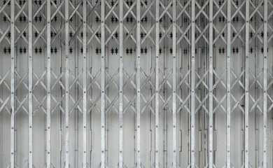 Folding old grey metal door gate. Expanded metal sliding gate. Old style grunge metal door. Rustic expanded metal shutter door close with lock pad.