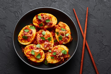 Golden Egg Curry in black bowl at dark slate background. Burmese Egg Curry is popular Myanmar Cuisine dish with duck or chicken eggs, tomatoes, ginger, onion, cilantro and spices.