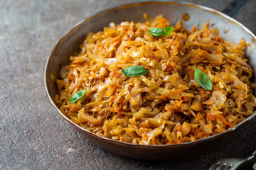 Stewed or braised cabbage served in a frying pan on dark stone background, close up