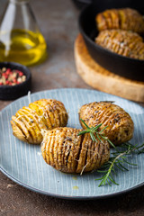 Baked hasselback potatoes with cheese, garlic and greens