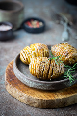 Obraz na płótnie Canvas Baked hasselback potatoes with cheese, garlic and greens