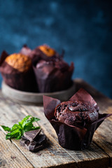Dark chocolate muffin with mint on a wooden table, homemade baking