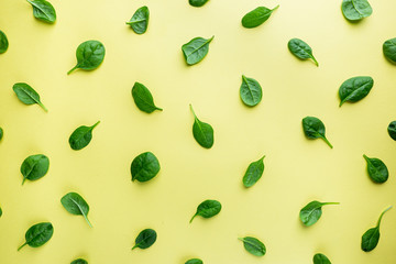 Spinach leaves pattern background on yellow, top view