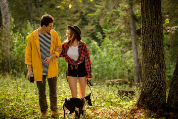 Young people with dog walking in autumn forest, free time, spare time, daily life, active lifestyle