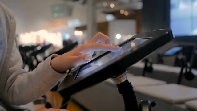 Woman hand using touchscreen display of interactive floor standing black tablet kiosk at exhibition or museum - side close up view. Futuristic, education, entertainment, learning, technology concept