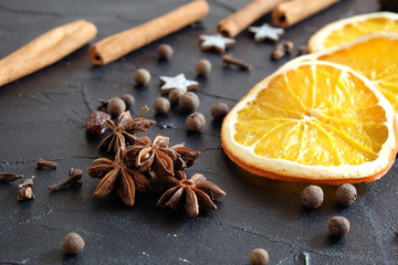 Festliche Gewürze auf dunklem Hintergrund mit Sternanis, Orangen, Nelken,  Zimt, Piment und Dekosternen © Manfred