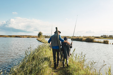 Caucasian father and son go on island in lake to find place for fishing. Warm and sunny day.