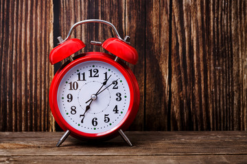 Red alarm clock on wooden table, time to wake up