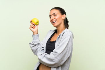 Young sport woman with an apple over isolated green background
