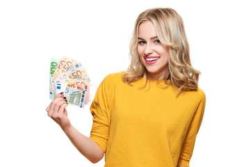 Young pretty woman in yellow sweater holding bunch of Euro banknotes, looking at camera and...