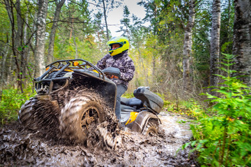 Man on ATV rides on a dirt road. Powerful transport. Off-road trip. Extreme rest. A trip through the autumn forest. Racing in nature. © Grispb