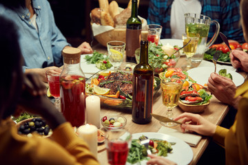 Close up of unrecognizable people enjoying dinner together, focus on delicious homemade food and...