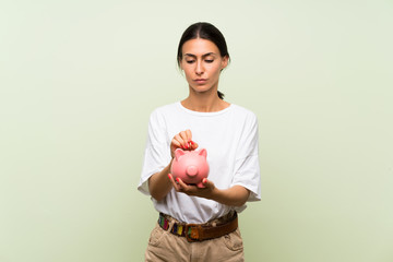 Fototapeta na wymiar Young woman over isolated green background holding a big piggybank