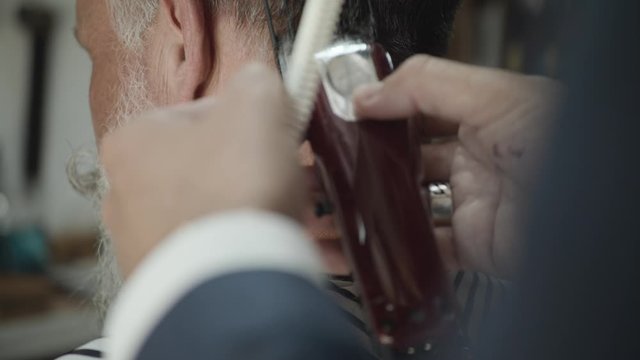 A barber cutting a man's neck hair with a trimmer