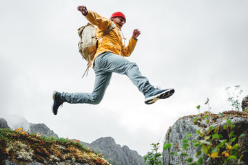 Active brave tourist jumping through cliff in mountain lifestyle outdoor journey. Man traveler with...