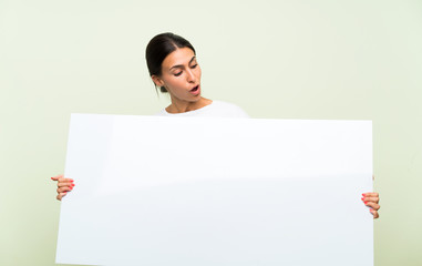 Young woman over isolated green background holding an empty white placard for insert a concept