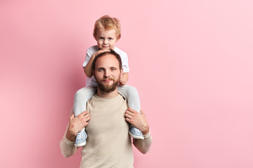 smiling bearded man and his son playing indoors, close up portrait, isolated pink background, people