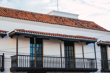 Wooden balcony in white wall. Colonial architecture