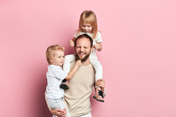 noisy naughty children torture their daddy.close up portrait, isolated pink background, studio shot
