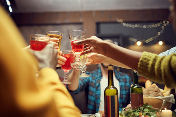 Low angle view at group of unrecognizable people raising glasses while toasting in celebration, copy space