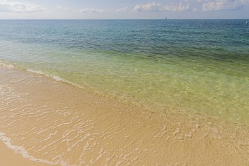 Beautiful view of Atlantic ocean sand beach. Yellow sand turning into dark blue water that merges  with light blue sky.  Key West, Florida. USA