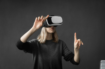 Young woman wearing virtual reality goggles headset, vr box. Connection, technology, new generation, progress concept. Girl trying to touch objects in virtual reality.