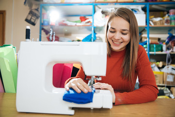 the master of sewing clothes works with the material, sewing on a typewriter in the workshop, preparing for the event, the hands of the master make even seams on the clothes,sewing machine