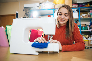 the master of sewing clothes works with the material, sewing on a typewriter in the workshop, preparing for the event, the hands of the master make even seams on the clothes,sewing machine