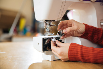 the master of sewing clothes works with the material, sewing on a typewriter in the workshop, preparing for the event, the hands of the master make even seams on the clothes,sewing machine