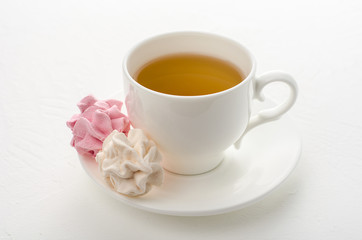 Cup of tea with marshmallows on a white background.