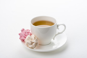 Cup of tea with marshmallows on a white background.