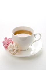 Cup of tea with marshmallows on a white background.