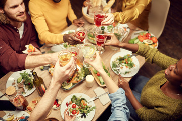Top view of people raising glasses over dinner table while enjoying party with friends, copy space