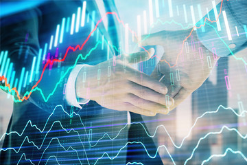 Double exposure of financial graph on cityscape background with two businessman handshake. Concept of stock market deal