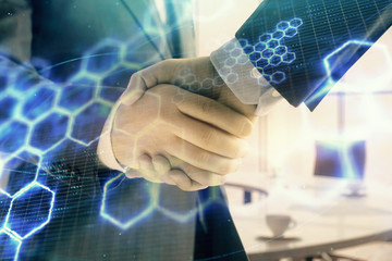 Multi exposure of tech theme hologram on office background with two men handshake. Concept of technology