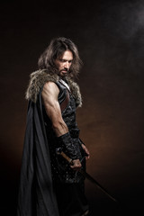 Man dressed in medieval armor and raincoat with longs word fighting against enemy. Courage fantasy...