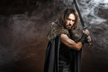 Portrait of a courageous ancient warrior in armor with sword and shield. Concept historical photo...