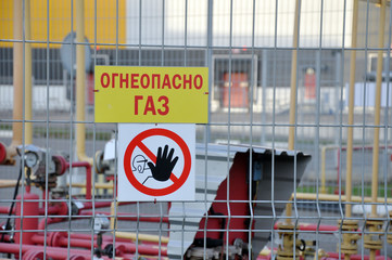 No entry sign on the fence. Gas distribution station in the background. Red circle and black hand.