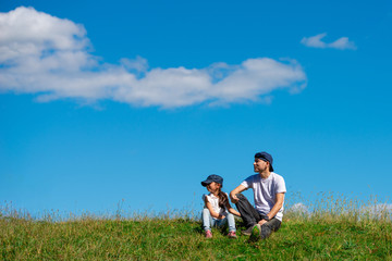 Fototapeta na wymiar 草原で座る父と娘